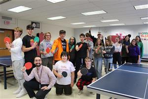 students with ping pong paddles smiling for camera 